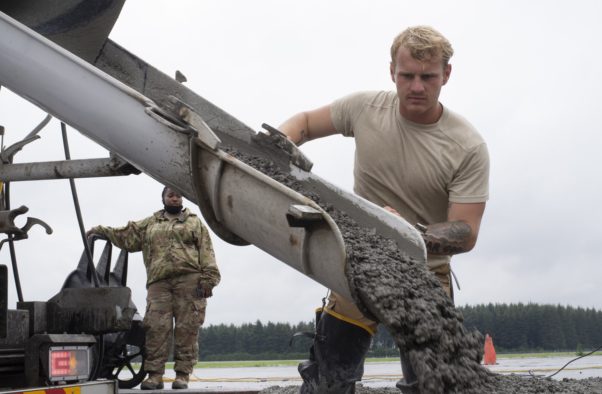 Senior Airman Zeke LaGrou, 823rd RED HORSE Squadron pavement and construction equipment journeyman, distributes wet concrete as part of a construction project to expand a flightline apron June 30, 2021, at Yokota Air Base, Japan. The construction project is the first 800th RED HORSE Group project within the U.S. Indo-Pacific and is led by the 823rd RED HORSE Squadron with support from the 819th and 820th RED HORSE Squadrons. The apron expansion is the first in an approximately four-year phased construction effort to enhance Yokota Air Base’s airlift mission capabilities. (U.S. Air Force photo by Tech. Sgt. Christopher Hubenthal)