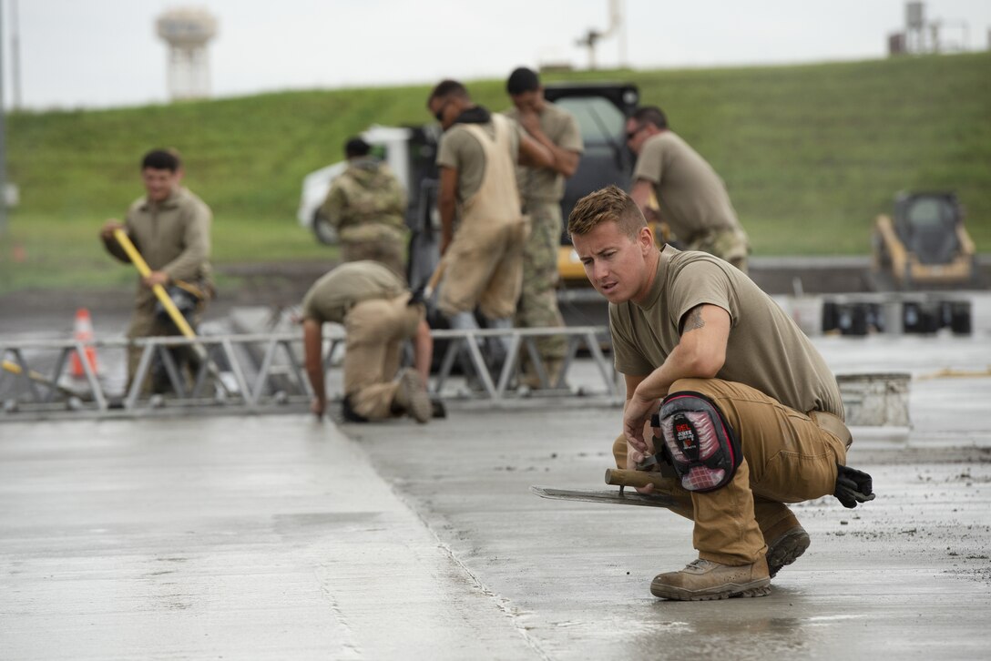 Senior Airman Riley Gervais, 823rd RED HORSE Squadron, pavement and construction equipment journeyman, inspects the quality of leveled wet concrete as part of a construction project to expand a flightline apron June 30, 2021, at Yokota Air Base, Japan. The construction project is the first 800th RED HORSE Group project within the U.S. Indo-Pacific and is led by the 823rd RED HORSE Squadron with support from the 819th and 820th RED HORSE Squadrons. The apron expansion is the first in an approximately four-year phased construction effort to enhance Yokota Air Base’s airlift mission capabilities. (U.S. Air Force photo by Tech. Sgt. Christopher Hubenthal)