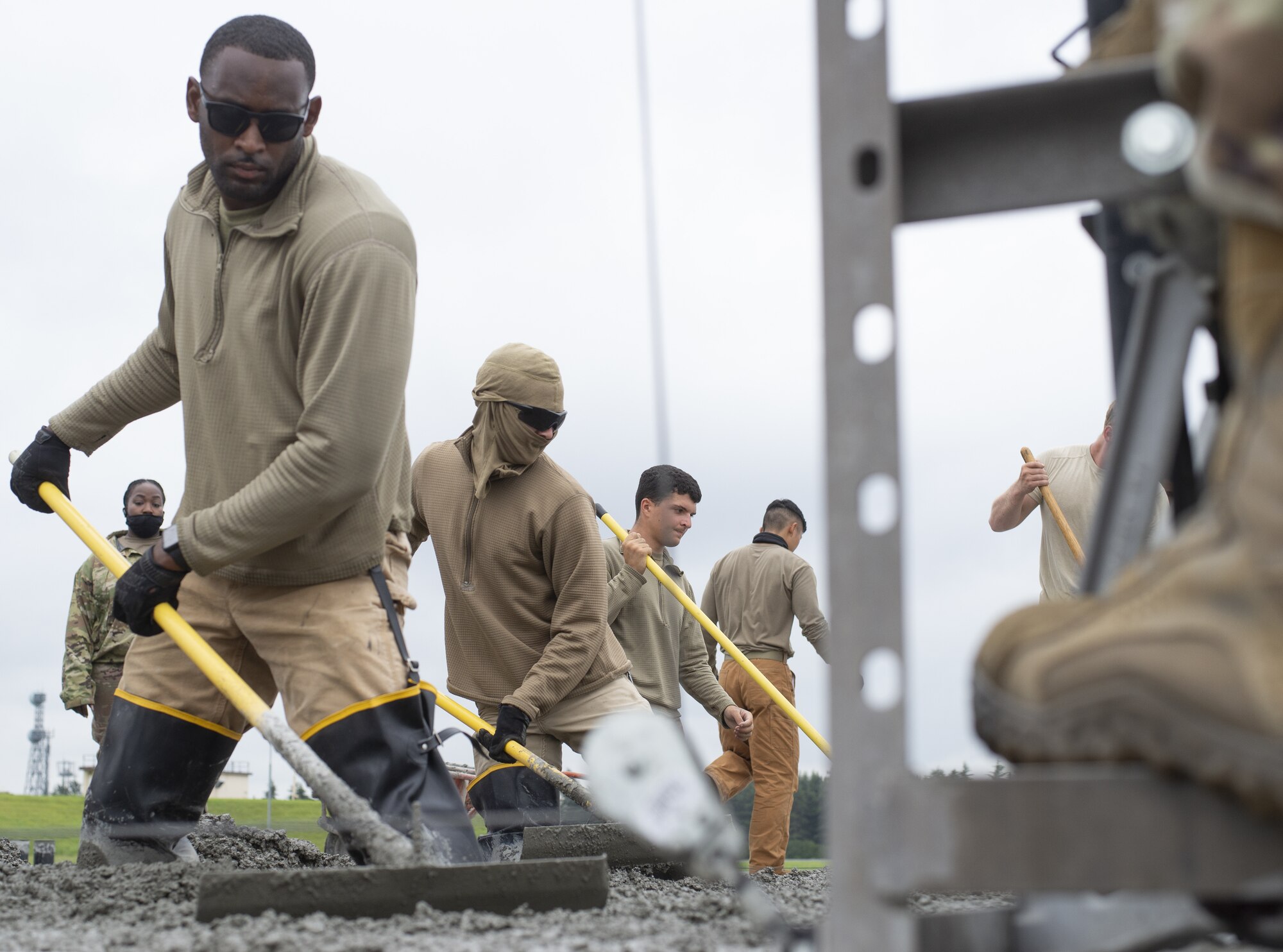Airmen assigned to the 800th RED HORSE Group, level wet concrete as part of a construction project to expand a flightline apron June 30, 2021, at Yokota Air Base, Japan. The construction project requires Airmen assigned to the 823rd, 819th and 820th RED HORSE Squadrons to pour approximately 7,300 cubic meters of concrete and pave 650 tons of asphalt in a construction effort to increase aircraft parking capabilities at Yokota Air Base. The apron expansion is the first in an approximately four-year phased construction effort to enhance Yokota Air Base’s airlift mission capabilities. (U.S. Air Force photo by Tech. Sgt. Christopher Hubenthal)