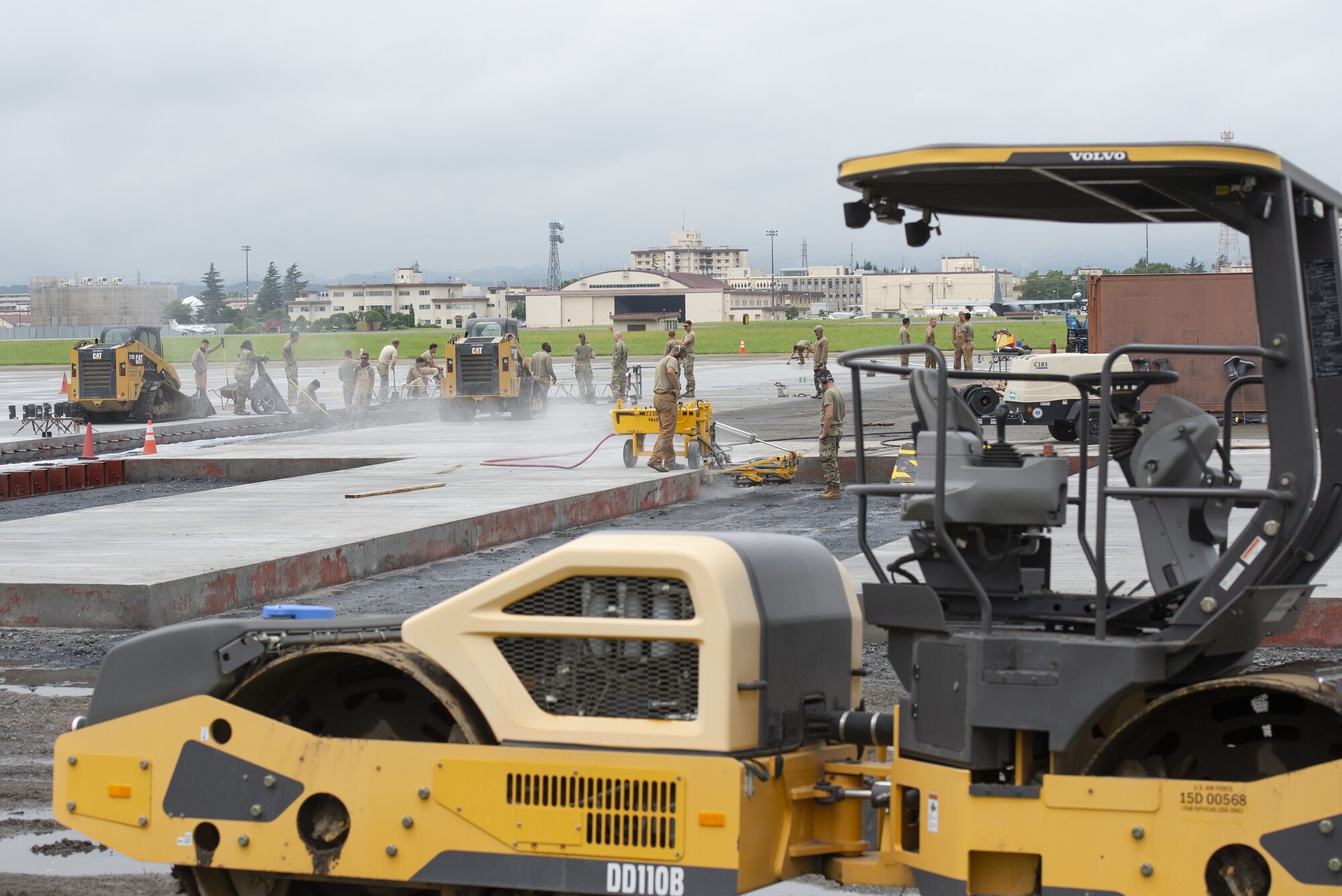 Airmen assigned to the 800th RED HORSE Group, work together in a construction effort to expand a flightline apron June 30, 2021, at Yokota Air Base, Japan. The construction project requires Airmen assigned to the 823rd, 819th and 820th RED HORSE Squadrons to pour approximately 7,300 cubic meters of concrete and pave 650 tons of asphalt in a construction effort to increase aircraft parking capabilities at Yokota Air Base. The apron expansion is the first in an approximately four-year phased construction effort to enhance Yokota Air Base’s airlift mission capabilities. (U.S. Air Force photo by Tech. Sgt. Christopher Hubenthal)