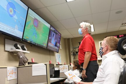 People observing weather systems on computer displays monitor a hurricane.