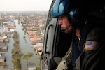 A person looks out of a helicopter at flooding.