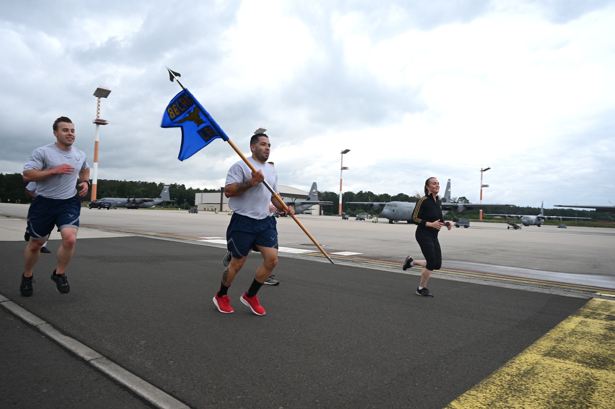 U.S. Air Force Airmen run past a pair of C-130 Hercules aircrafts during the RUNway 5K at Ramstein Air Base, Germany, July 1, 2021. Every Squadron from the 86th Airlift Wing participated in the RUNway 5K as a way to promote a healthy and fit force. (U.S. Air Force photo by Senior Airman Thomas Karol)