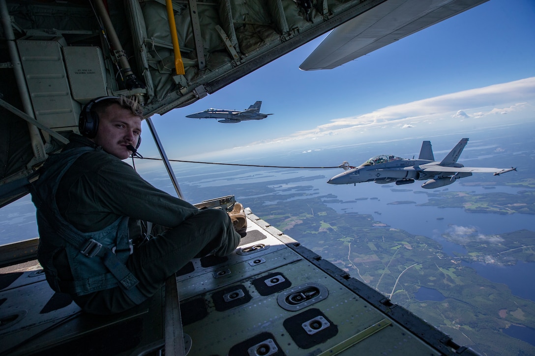 U.S. Marine Corps Cpl. Cole Kennedy, a native of Bertrand, Nebraska, guides a U.S. Marine Corps F/A-18 Super Hornets assigned to Marine Fighter Attack Squadron (VMFA) 115 to refueling lines from a KC-130J Super Hercules during aerial refueling over Rissala Air Base, Kuopio, Finland, June 8, 2021. Marines with VMFA-115 are deployed to Kuopio, Finland in support of Squadron Visit ILVES (Finnish for “Lynx”). The purpose of Squadron Visit ILVES is to conduct air-to-air and air-to-ground training, improve proficiency in joint and multinational tactics, and enhance partnerships with international allies. VMFA-115 is a subordinate unit of 2nd Marine Aircraft Wing, the aviation combat element of II Marine Expeditionary Force. (U.S. Marine Corps photo by Lance Cpl. Caleb Stelter)