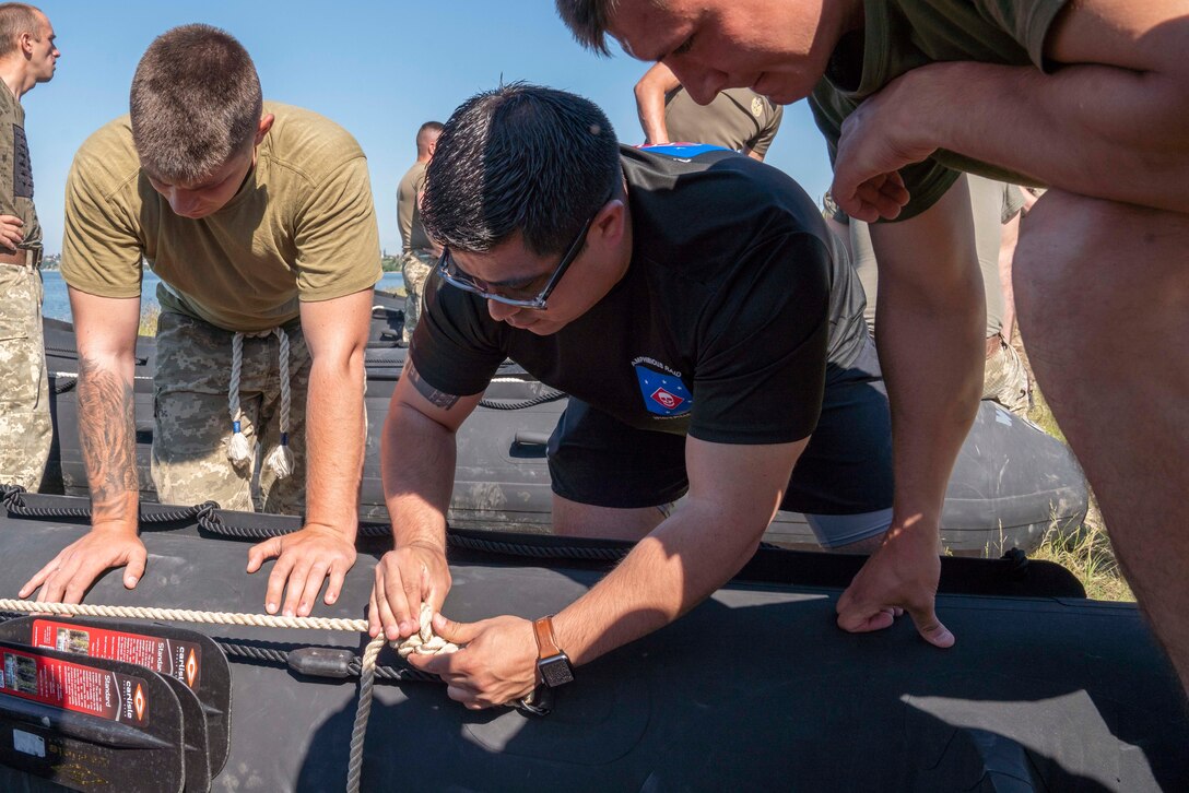 U.S. Marine Corps Gunnery Sgt. Daniel Mata, an infantry unit leader with U.S. Marine Corps Forces Europe and Africa, examines knots tied by Ukrainian Marines from the 36th Marine Brigade during a combat rubber reconnaissance craft (CRRC) practical application class in Mykolayiv, Ukraine, June 9, 2021. During a nine-day period of instruction, U.S. Marines will teach Marines from Ukraine the basics of operating with the CRRC, a small, lightweight, inflatable, yet rugged boat, useful in a variety of missions requiring speed and stealth. (U.S. Marine Corps photo by Cpl. Claudia Nix)