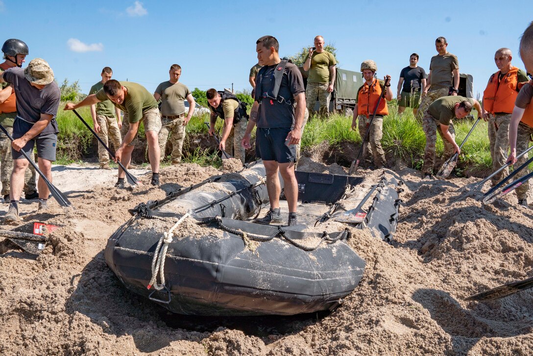 U.S. Marine Corps Staff Sgt. Tyler Ochs, center, an infantry unit leader with Expeditionary Warfare Training Group, Pacific, teaches Ukrainian Marines from the 36th Marine Brigade how to conceal a combat rubber reconnaissance craft (CRRC) in Mykolayiv, Ukraine, June 9, 2021. During a nine-day period of instruction, U.S. Marines will teach Marines from Ukraine the basics of operating with the CRRC, a small, lightweight, inflatable, yet rugged boat, useful in a variety of missions requiring speed and stealth. (U.S. Marine Corps photo by Cpl. Claudia Nix)