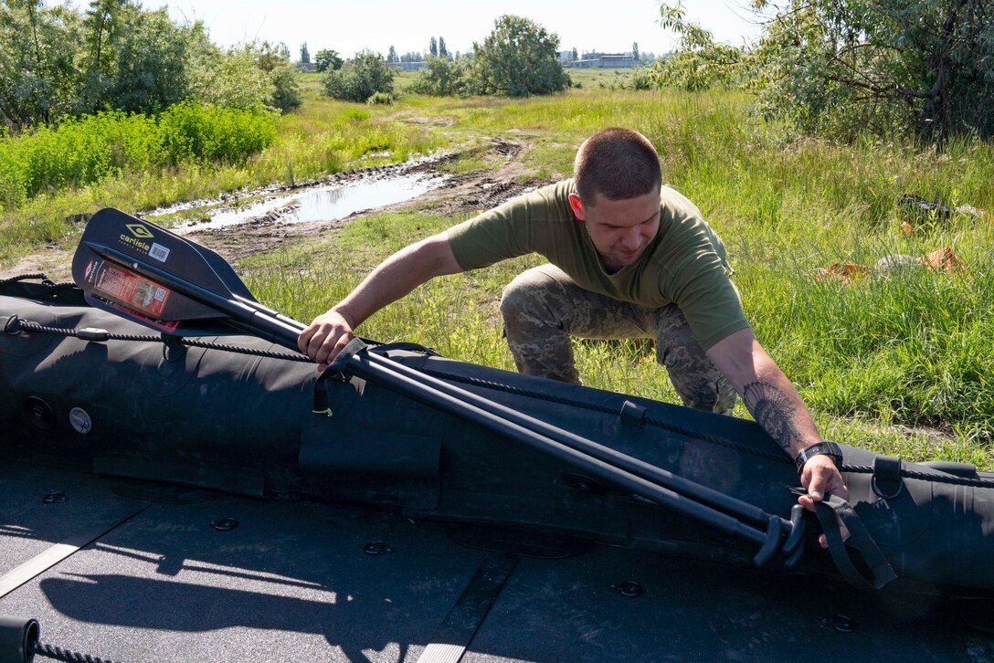 A Ukrainian Marine with the 36th Marine Brigade attaches oars to a combat rubber reconnaissance craft (CRRC) in Mykolayiv, Ukraine, June 9, 2021. During a nine-day period of instruction, U.S. Marines will teach Marines from Ukraine the basics of operating with the CRRC, a small, lightweight, inflatable, yet rugged boat, useful in a variety of missions requiring speed and stealth. (U.S. Marine Corps photo by Cpl. Claudia Nix)