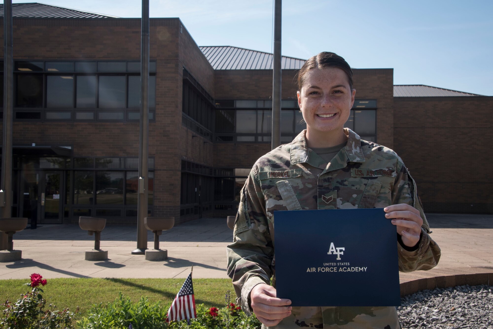 Senior Airman Alivia Merkel, a dental technician at the 179th Airlift Wing, stands outside wing headquarters holding her letter of acceptance to the Air Force Academy at the 179th Airlft Wing in Mansfield, Ohio, June 23, 2021. After three years of service at the 179th Airlift Wing, Merkel has been offered an opportunity to further her education while commissioning in the World’s Greatest Air Force. (U.S. Air National Guard photo by Airman First Class Grace Riegel)