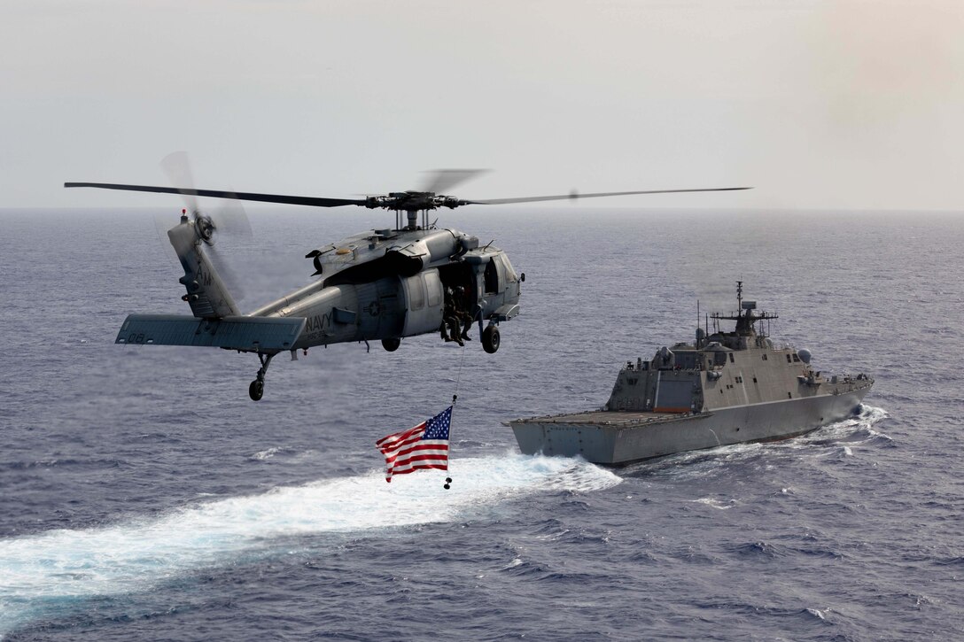 A helicopter flies above a ship in the ocean.