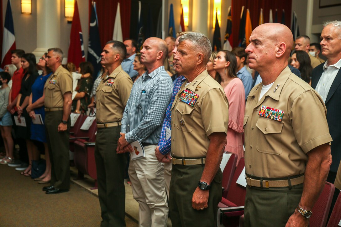 Guests stand at attention during the Marine Hymn at the Headquarters Battalion, Training and Education Command, change of command ceremony at Breckinridge Hall on Marine Corps Base Quantico, Virginia, June 25, 2021. A change of command signifies a formal transfer of authority and responsibility for a unit from one commander to another. (U.S. Marine Corps Photo by Lance Cpl. Mitchell Johnson)