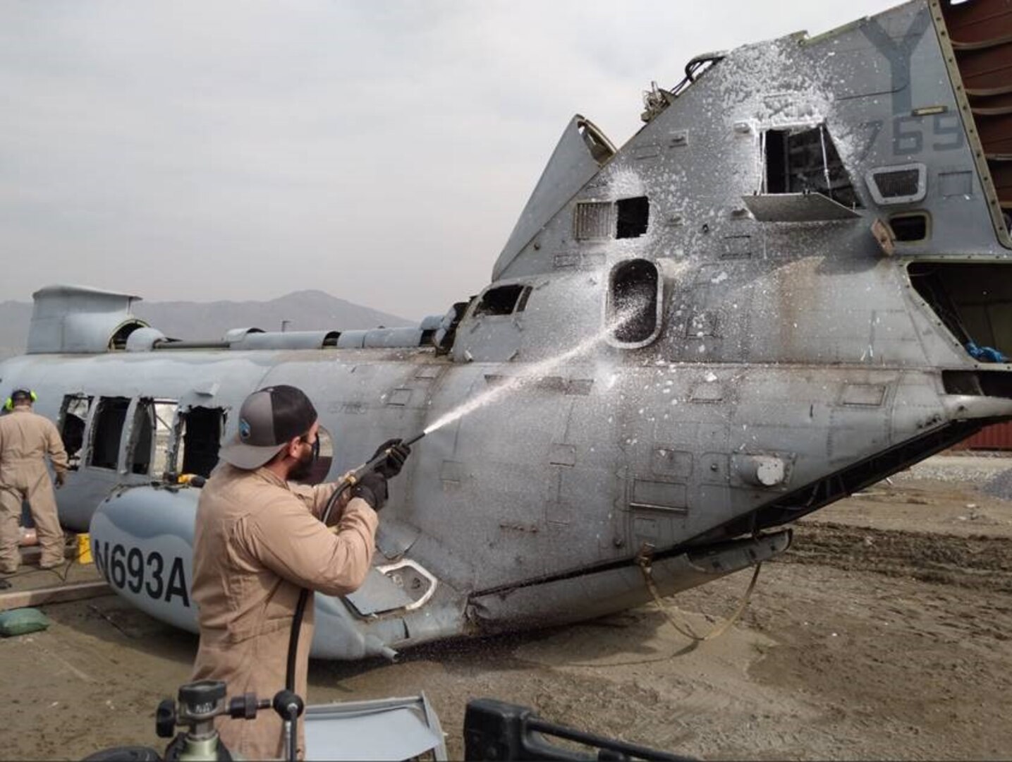 medic sprays helicopter hull with fire suppressing material