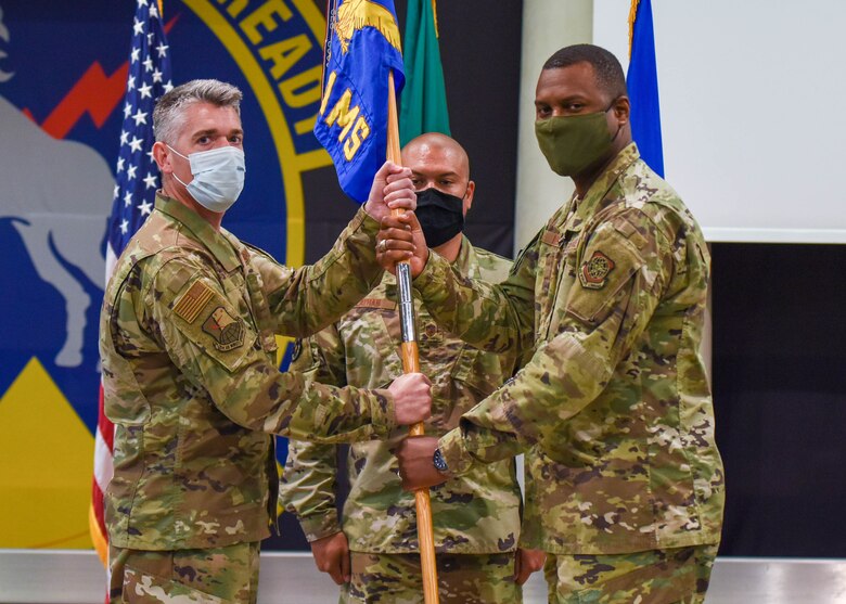 U.S. Air Force Col. Christopher Busque, 31st Mission Support Group commander, left, passes the guidon to U.S. Air Force Lt. Col. Anthonelli White, 724th Air Mobility Squadron outgoing commander, during a change of command ceremony at Aviano Air Base, Italy, July 6, 2021. The 724th AMS has 44 military and civilian employees is the smallest squadron out of 11 air mobility squadrons in the U.S. European Command. (U.S. Air Force photo by Airman 1st Class Brooke Moeder)