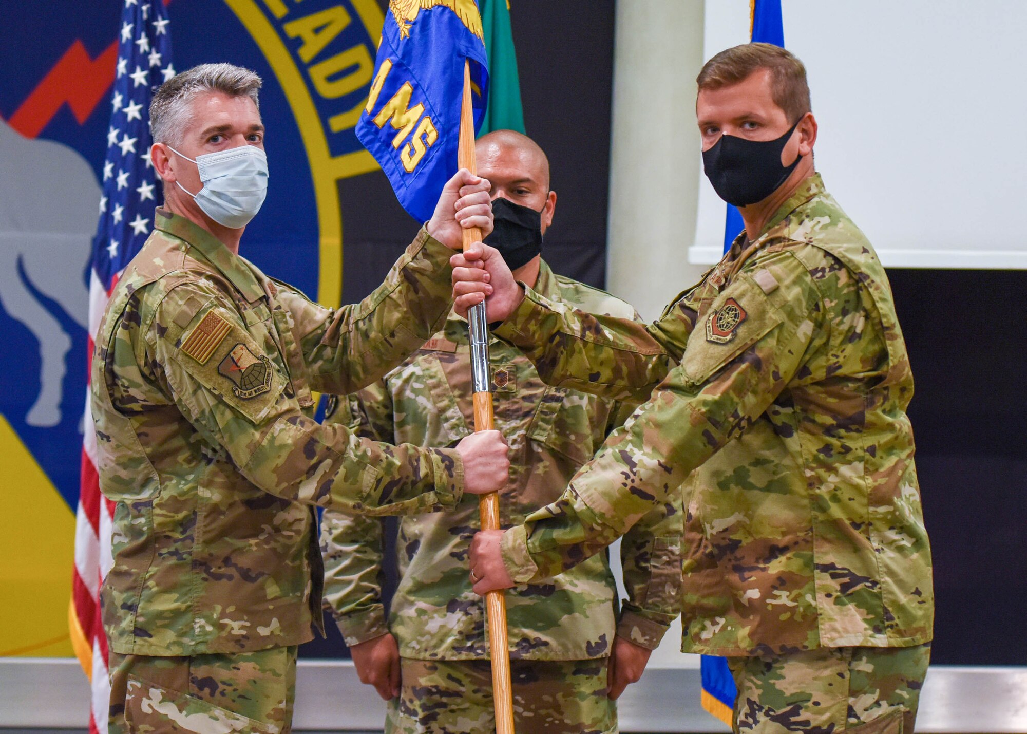 U.S. Air Force Col. Christopher Busque, 31st Mission Support Group commander, left, passes the guidon to U.S. Air Force Maj. Phillip Kapets, 724th Air Mobility Squadron incoming commander, during a change of command ceremony at Aviano Air Base, Italy, July 6, 2021. The 724th AMS is made up of two flights, the operations flight and the combat readiness and resources flight and the operations flight performs inspections and loads cargo and passengers on AMC aircraft while the resources flight ensures the operations flight has all the resources needed to load and unload the jets. (U.S. Air Force photo by Airman 1st Class Brooke Moeder)