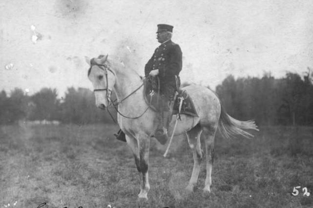 A soldier sits on a horse in a field.
