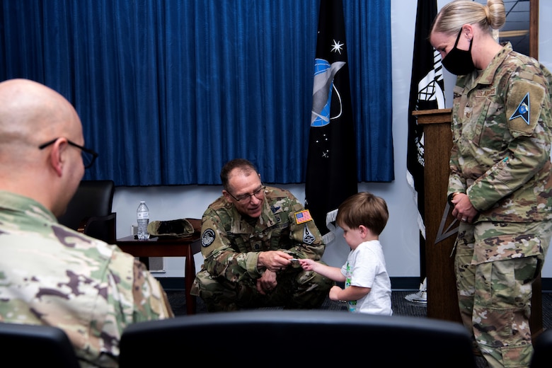 Chief Master Sgt. of the Space Force Roger A. Towberman awards his personal coin to Apollo Meza, 3, son of U.S. Air Force Tech. Sgt. Victoria Meza, Vosler Non-Commissioned Officer Academy Professional Military Education instructor at Peterson Air Force Base, Colorado, July 1, 2021. Towberman presented the VNCOA the Department of the Air Force NCOA of the Year award which recognizes outstanding performance and exceptional contributions that support professional military education across the Air Force. (U.S. Space Force photo by Airman 1st Class Joshua Fontenot)