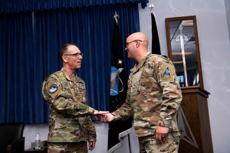 Chief Master Sgt. of the Space Force Roger A. Towberman awards his personal coin to U.S. Space Force Senior Master Sgt. Adrian Gaxiola, Vosler Non-Commissioned Officer Academy director of education, Peterson Air Force Base, Colorado, July 1, 2021. The VNCOA launched the first-ever NCOA virtual in-residence remote course allowing the continuation of professional military education during the COVID-19. The VNCOA coordinated with the Barnes Center for Enlisted Education to validate Community College of the Air Force requirements and develop a virtual education plan which saved the Air Force $1.8 million in temporary duty costs. (U.S. Space Force photo by Airman 1st Class Joshua Fontenot)