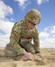 solider kneeling in the dirt inspecting a simulated mine