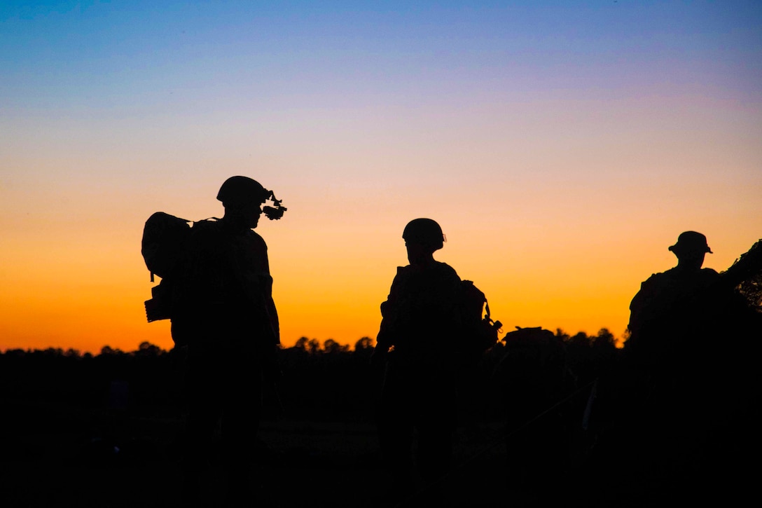Three Marines shown in silhouette.