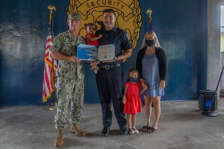 Jeff Chargualaf poses with his family and U.S. Navy Capt. Jeffrey Grimes, commanding officer, U.S. Naval Base Guam (NBG), during a graduation ceremony for newly hired police officers on NBG, July 6, 2021.