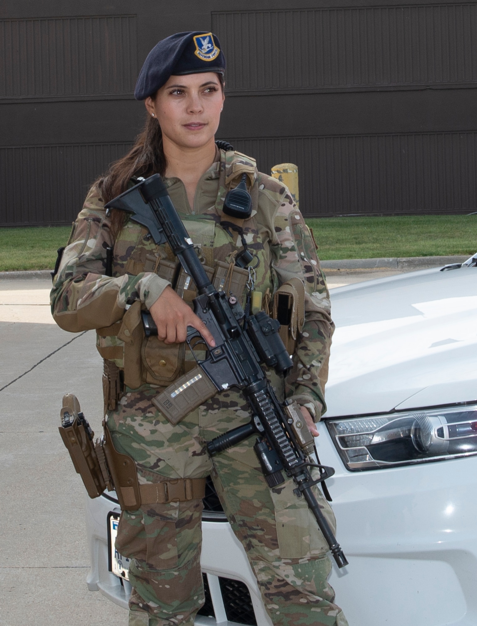 Close up of female Airman in uniform standing guard in front of Security Forces vehicle as she holds her weapon. Female is wearing new body armor for women