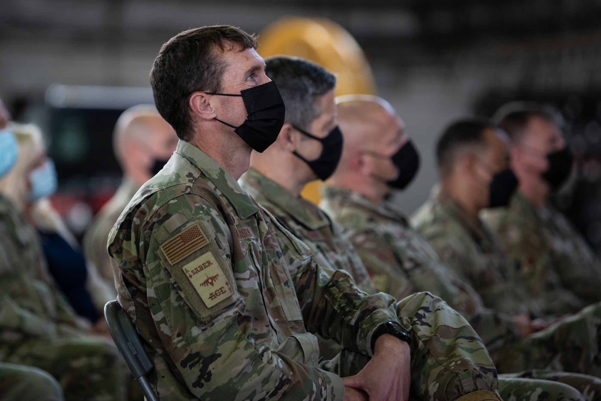 U.S. Air Force Col. David Epperson, 52nd Fighter Wing commander, and other audience members listen to a speech during the 52nd Aircraft Maintenance Squadron assumption of command, July 6, 2021, on Spangdahlem Air Base, Germany. Assumptions of command ceremonies consist of passing a guidon to the incoming commander, then following with the incoming commander giving their first salute and taking command of the squadron. (U.S. Air Forces photo by Staff Sgt. Melody W. Howley)