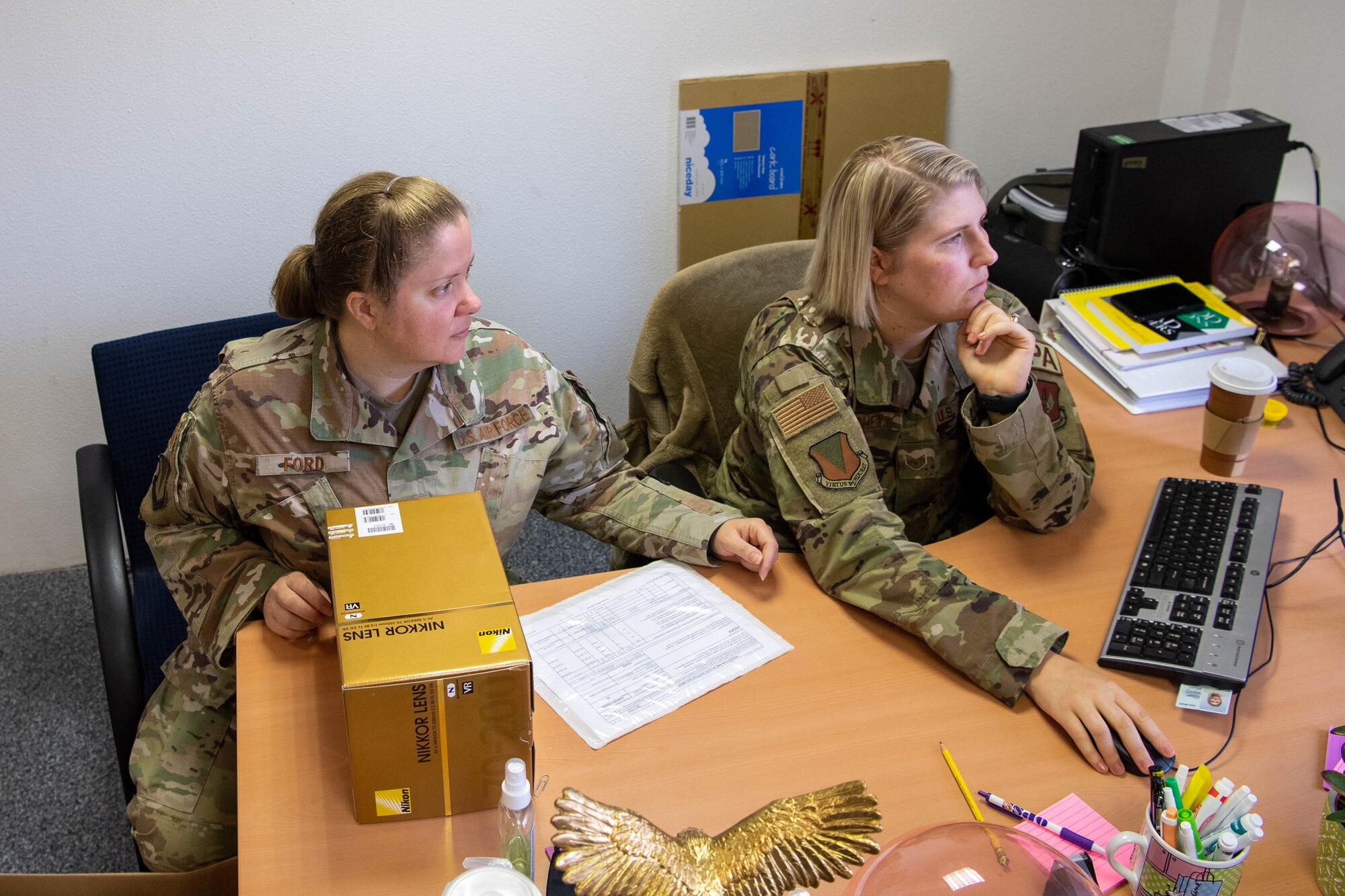 Airmen sit at a desk