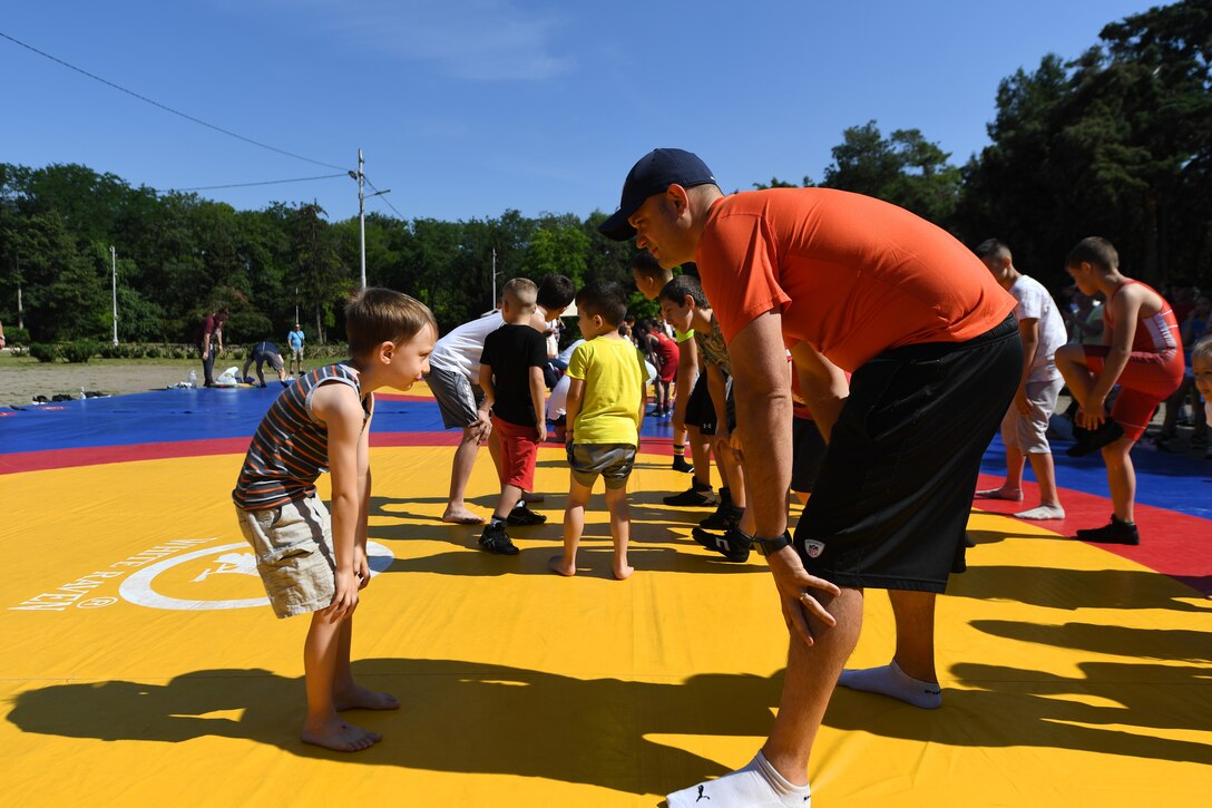 Sailors play games with kids at a playground.