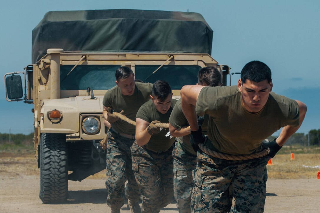 Marines use a rope to pull a military vehicle.