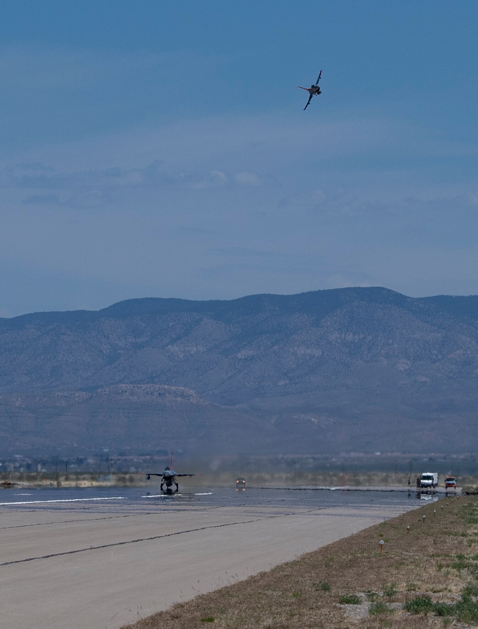 A QF-16 Full Scale Aerial Target maneuvers next to another QF-16 to monitor its take off during a dress rehearsal for an upcoming missile test at Holloman Air Force Base, New Mexico. (U.S. Air Force photo by Tech. Sgt. Perry Aston)