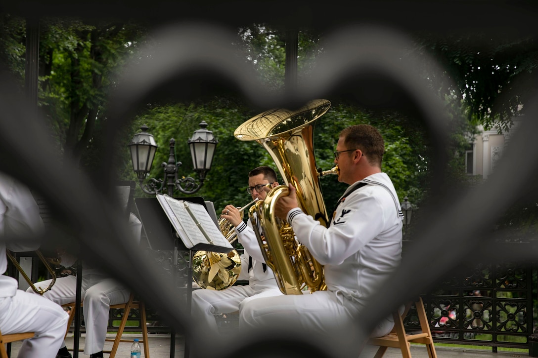 A band performs as seen through a piece of a heart-shaped fence.