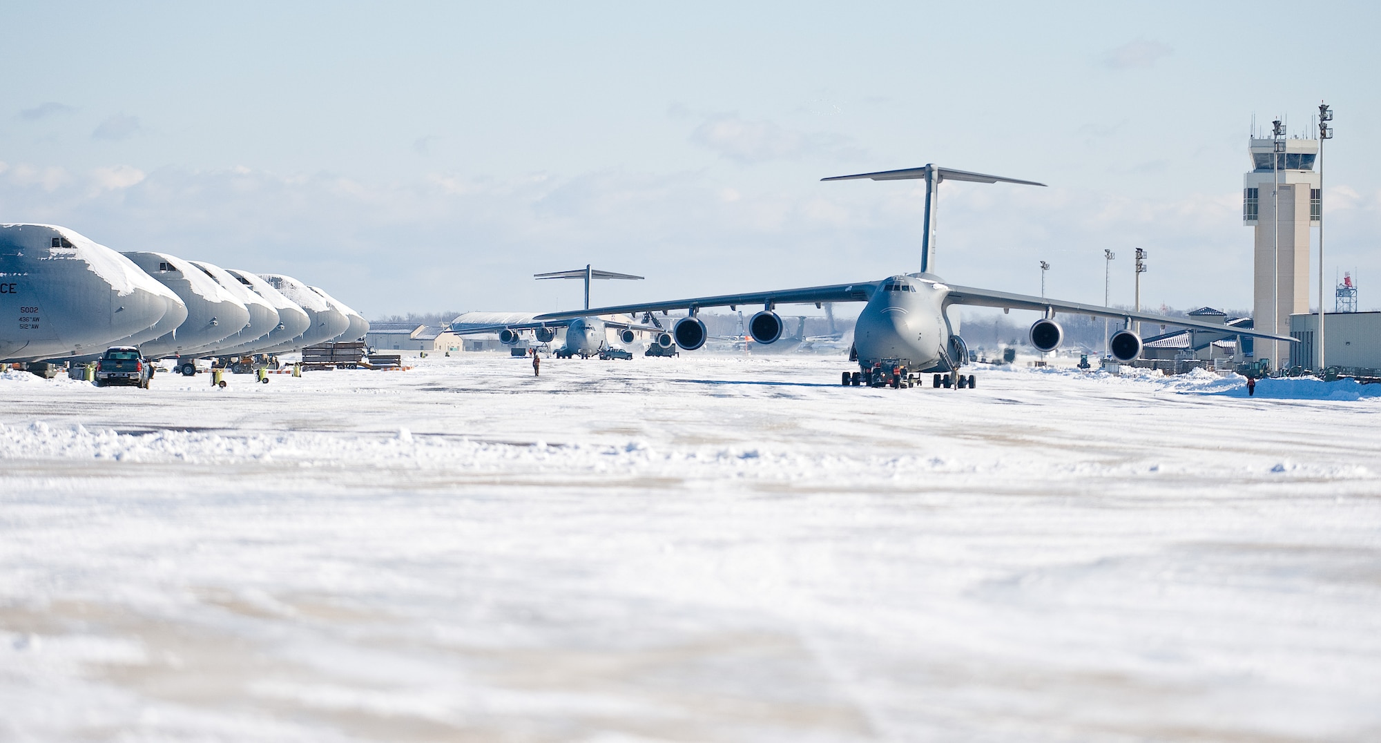 U.S. Airmen tow a C-5M Super Galaxy aircraft at Dover Air Force Base, Del., Jan. 3, 2014. Airmen with the 436th Civil Engineer Squadron cleared snow from the flight line after a storm. (U.S. Air Force photo by Roland Balik/Released)