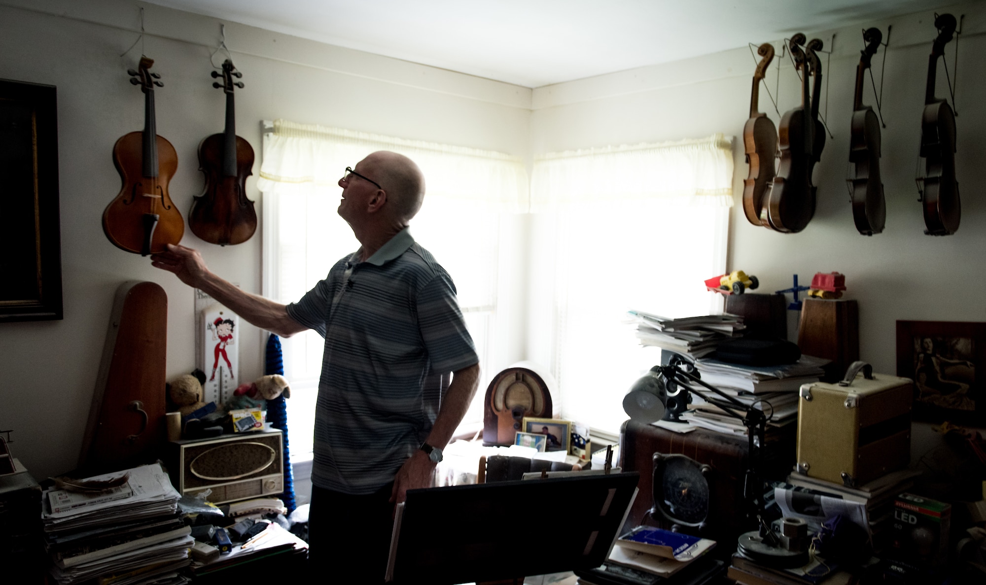 Retired U.S. Air Force Master Sgt. Daniel Holmes, picks up one of his handmade violins at his home in Lowell, Mass., Jun. 1, 2018. Holmes teaches Airmen various electronic and mechanical skills not taught during their technical training in order for them to maintain 1960's era technology used  at the Sagamore Hill Solar Observatory of the 2nd Weather Squadron, Det. 2, in Hamilton, Mass. (U.S. Air Force photo by J.M. Eddins Jr.)