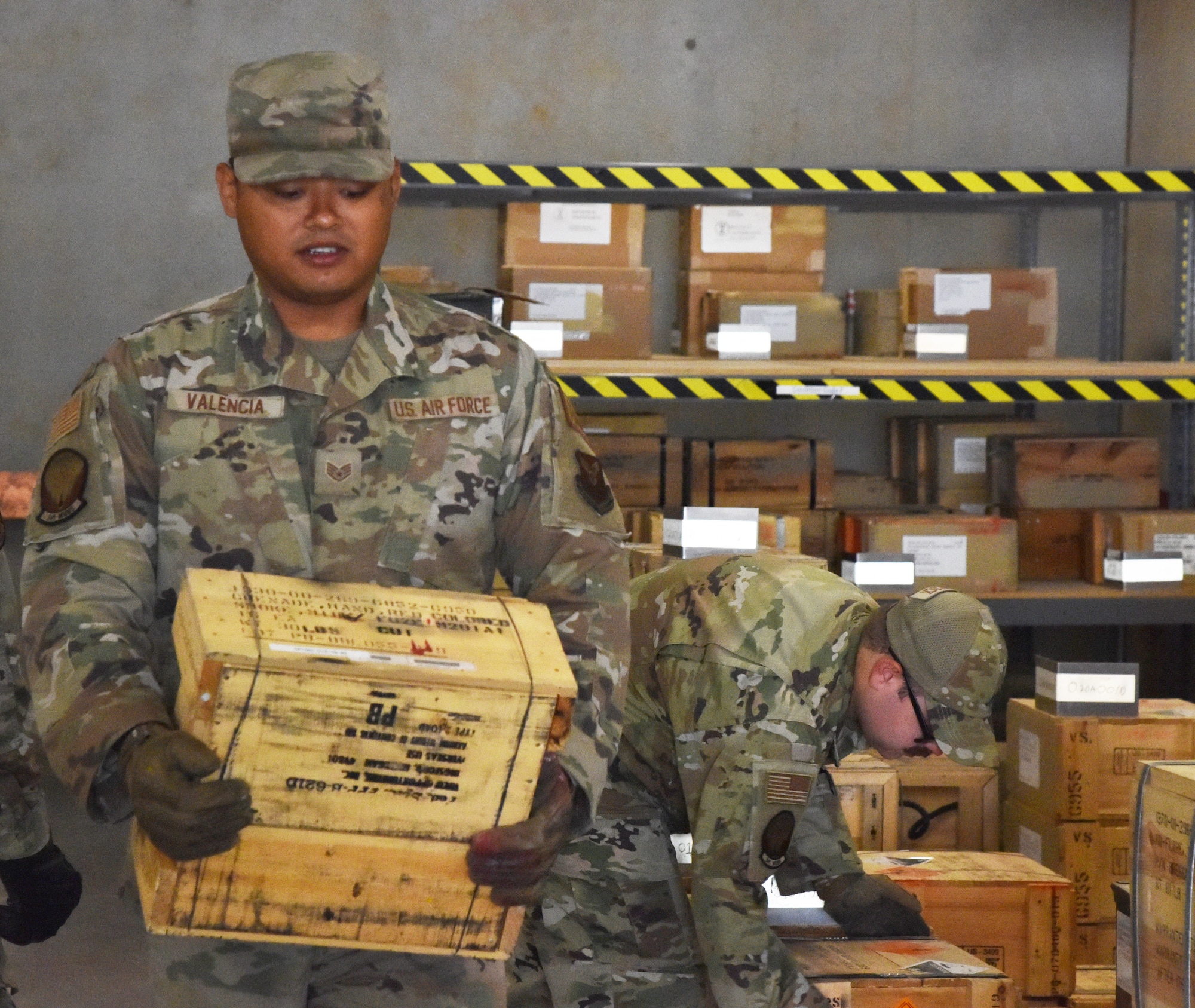 Staff Sgt. Arvin Valencia, 341st Munitions Squadron materiel flight munitions inspector, lifts a box of red smoke grenades for issue July 6, 2021, at Malmstrom Air Force base, Mont. Munitions Airmen store, maintain, inventory and issue explosive materials for use by other units on the base. (U.S. Air Force photo by Tech. Sgt. Joseph Park)