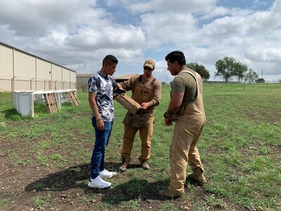 Airmen help student put on arm sleeve for an MWD demonstration.