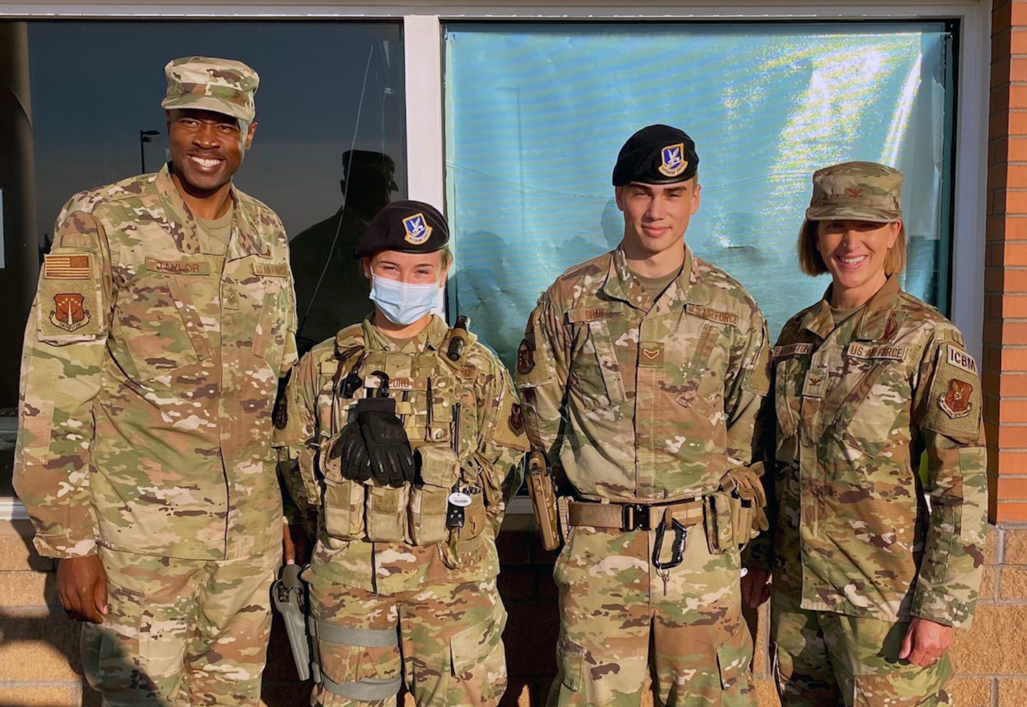 Chief Master Sgt. Nicholas Taylor, 90th Missile Wing command chief, Airman Suzanne Pedro, Airman 1st Class Frank Shaw, both from 90th Security Forces Squadron, and Col. Catherine Barrington, 90 MW commander, pose for a photo on F.E. Warren Air Force Base, Wyoming, July 7, 2021. The Airmen were coined by wing leadership in recognition of excellence while performing their duties. Their actions in defending the base directly contributed to the capture of an individual with active arrest warrants and the recovery of a missing child. (Courtesy photo)