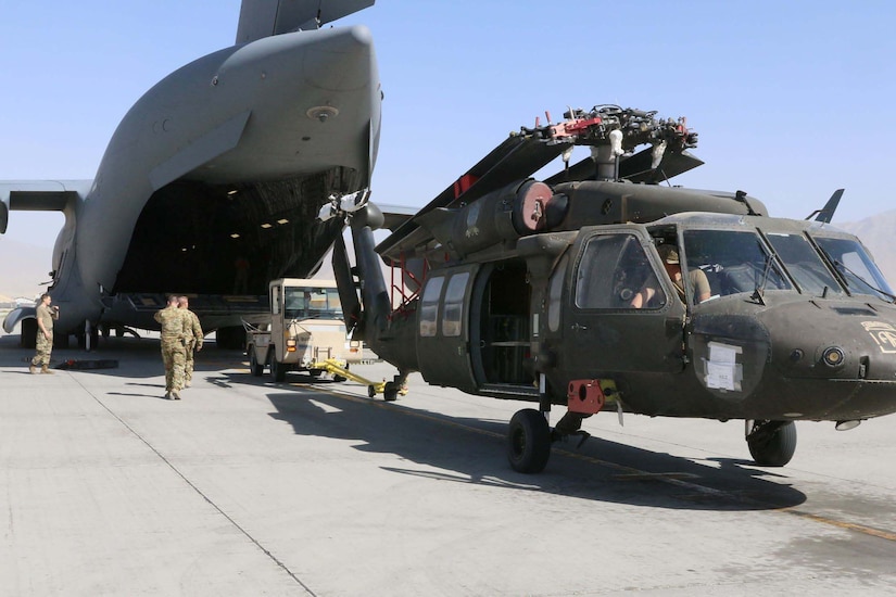 Troops load a helicopter into an airplane.