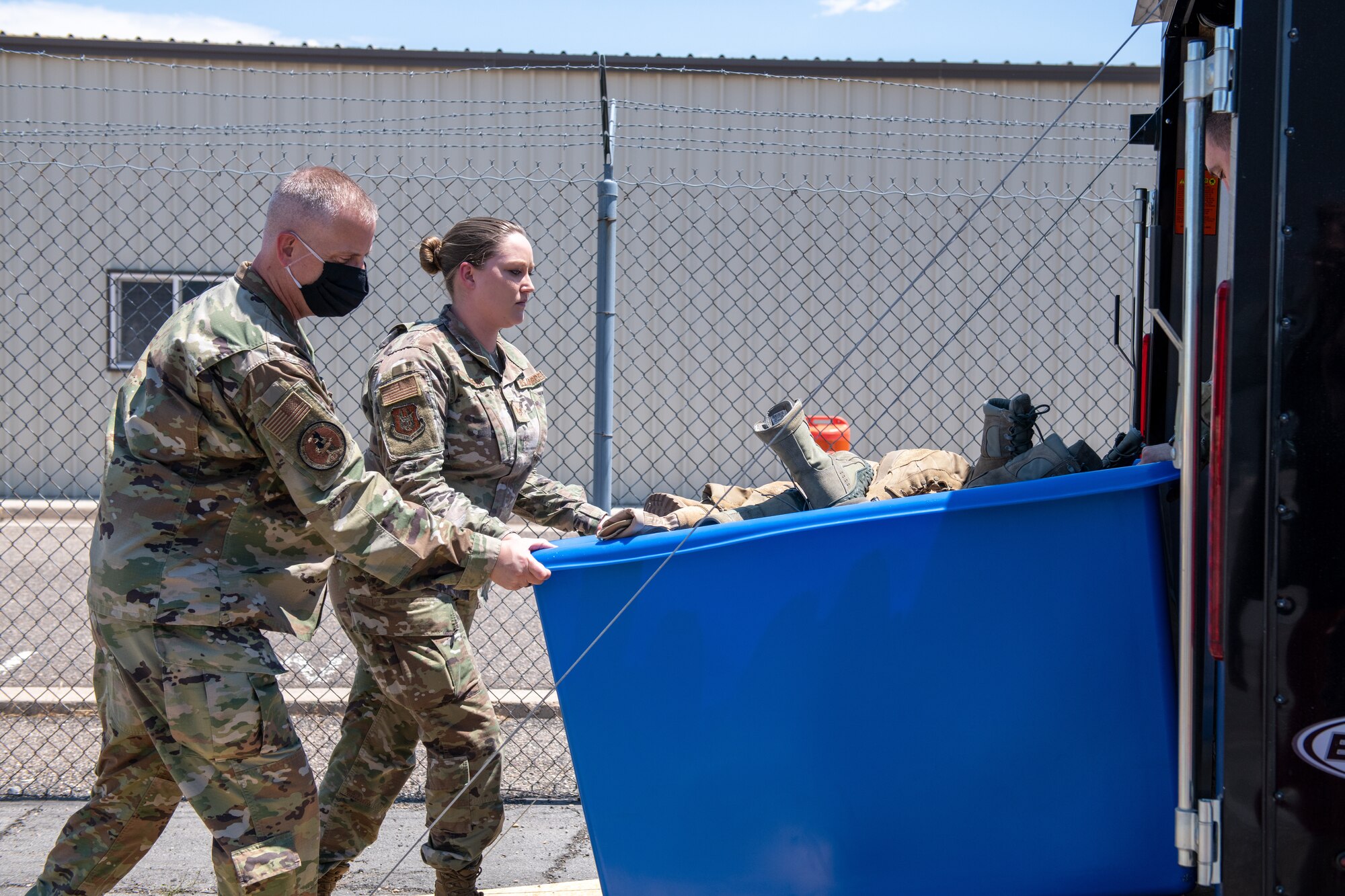 Col. Brett Newman, 419th Maintenance Group commander, helps Staff Sgt. Jayci Winter from the 419th MXG push a cart of collected boots into a trailer for a boot drive at Hill Air Force Base, Utah, on July 7, 2021.