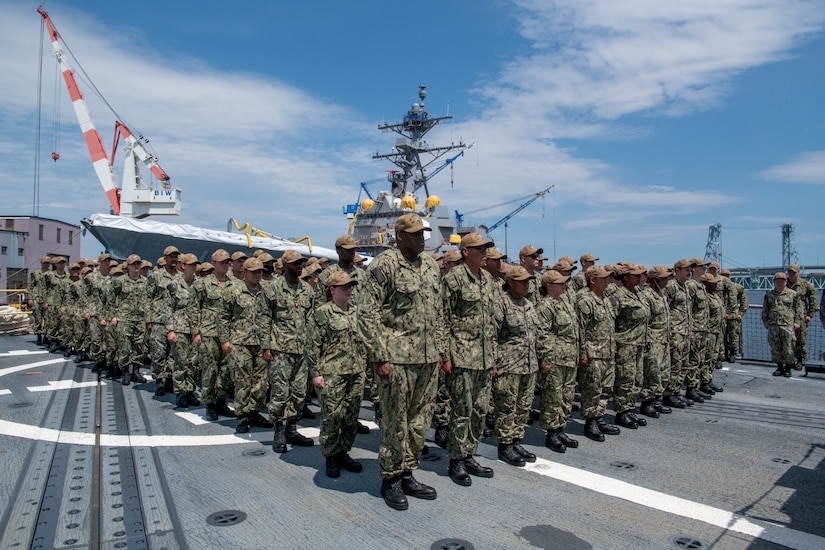 Service members stand on the deck of a ship.