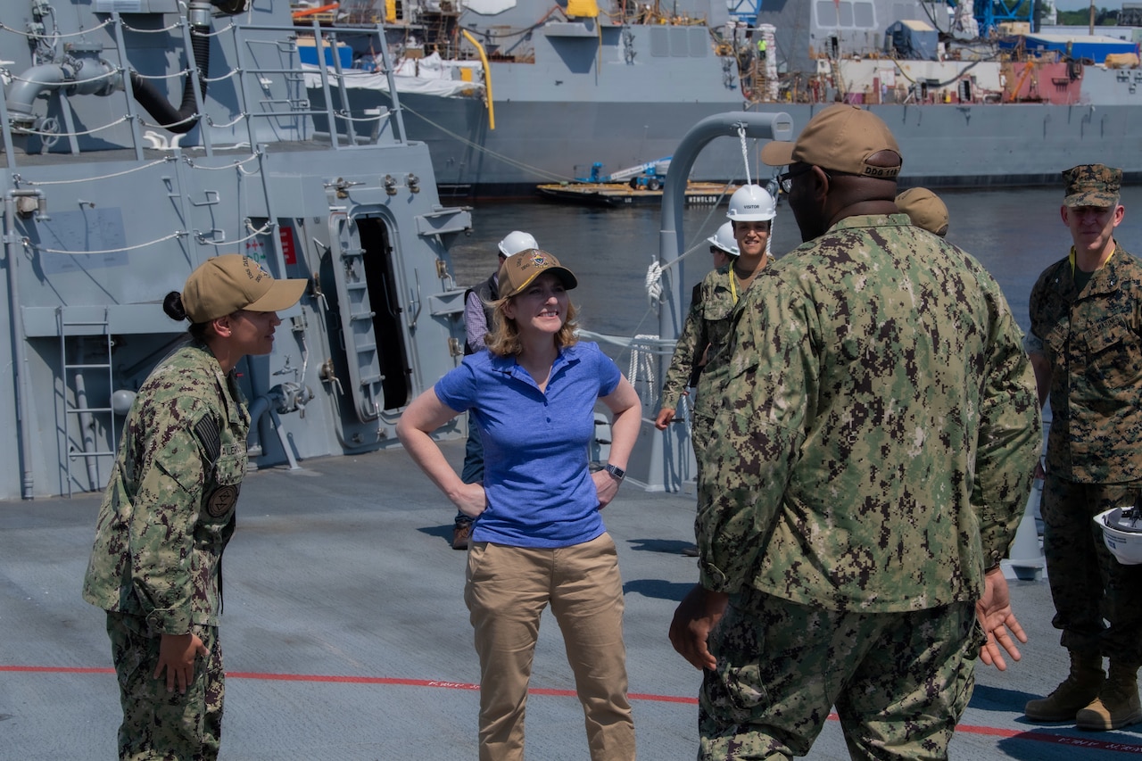 A woman talks to sailors.