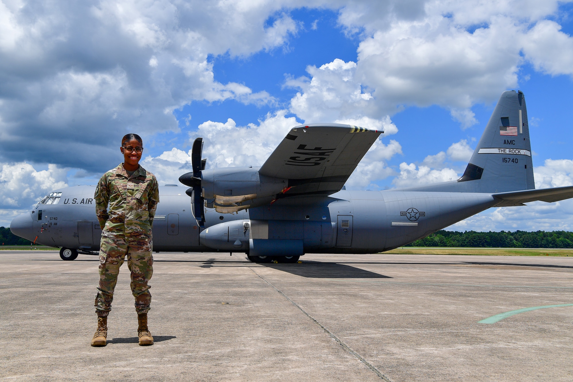 An airman poses for a photo in front of a C-130.