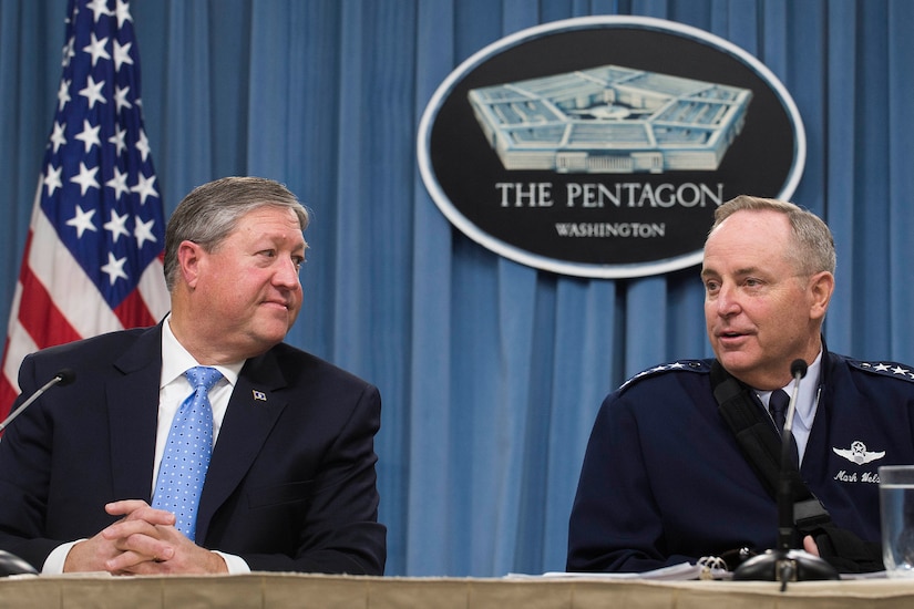 A man answers questions as another man looks on.