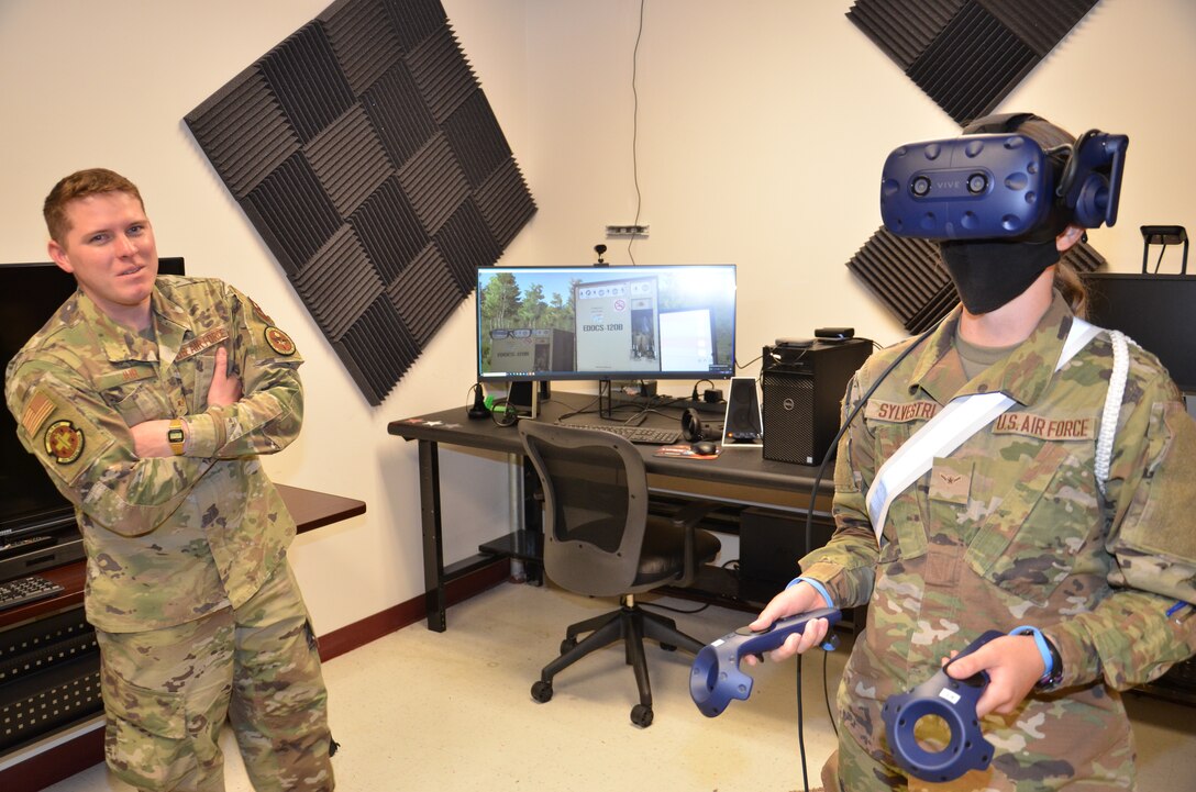 Air Force Staff Sgt. Austin Jur, a METC Biomedical Equipment Technician (BMET) program instructor, watches as Air Force Airman Lisa Sylvestri, a METC Radiologic Technologist student, tries out a  virtual reality device designed for BMET training during an Alamo Spark cell meeting. Some METC students were invited to the meeting in order to learn about the cell's mission, and were introduced to a variety of innovations to garner interest in becoming student volunteers.