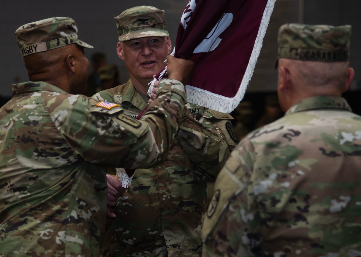 Commanding general passes unit colors to incoming commander during a change of command ceremny.