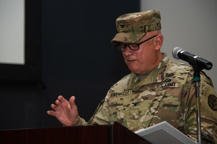 Outgoing DHCC commander speaks at podium during a change of command ceremony.