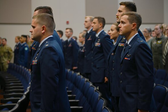 Graduates from Specialized Undergraduate Pilot Training Class 21-12 stand as they await to be presented their awards July 9, 2021, on Columbus Air Force Base, Miss. The graduates completed a 52-week pilot training program including academics, physiological training, and flight training in the T-6A Texan II, T-1A Jayhawk, and T-38C Talon. (U.S. Air Force photo by Airman First Class Jessica Haynie)