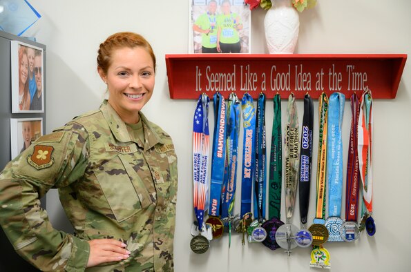 Airman stands in front of a display of her race medals.