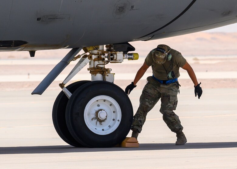 U.S. Air Force Tech. Sgt. Adam Barrett, 157th Expeditionary Fighter Generation Squadron F-16 dedicated crew chief, places chalks on a U.S. Air Force KC-135 Stratotanker for a hot-pit refueling, Prince Sultan Air Base, June 25, 2021. This event demonstrated the success of several weeks of hot-pit refueling cross-airframe training between 378th and 379th Air Expeditionary Wing maintainers, expanding both Wings ability to provide agile support for theater operations. (U.S. Air Force photo by Senior Airman Samuel Earick)