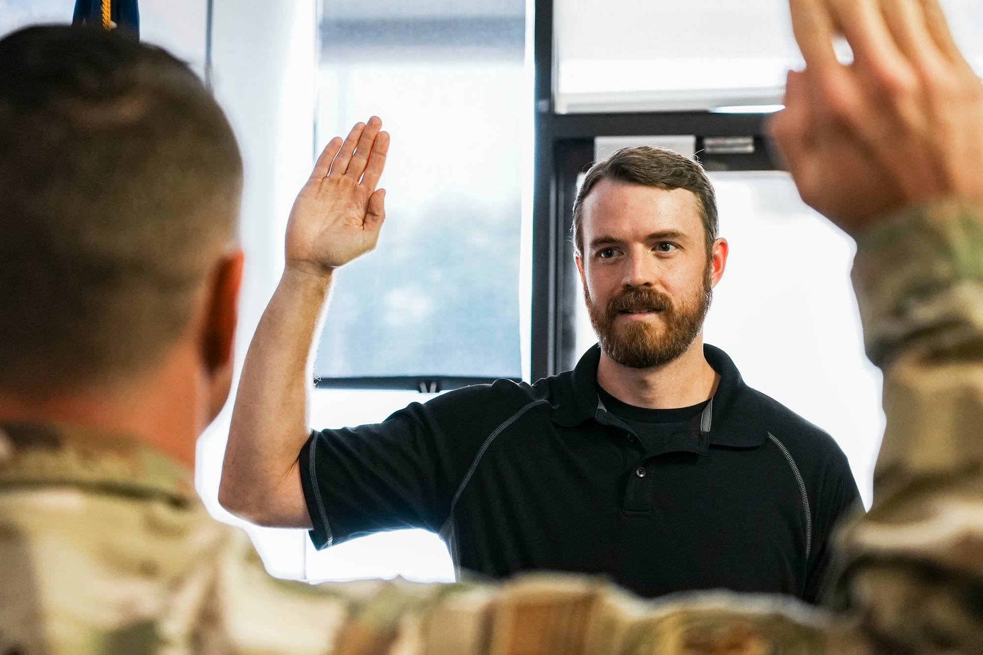 Man holds hand up to take the Oath of Enlistment.