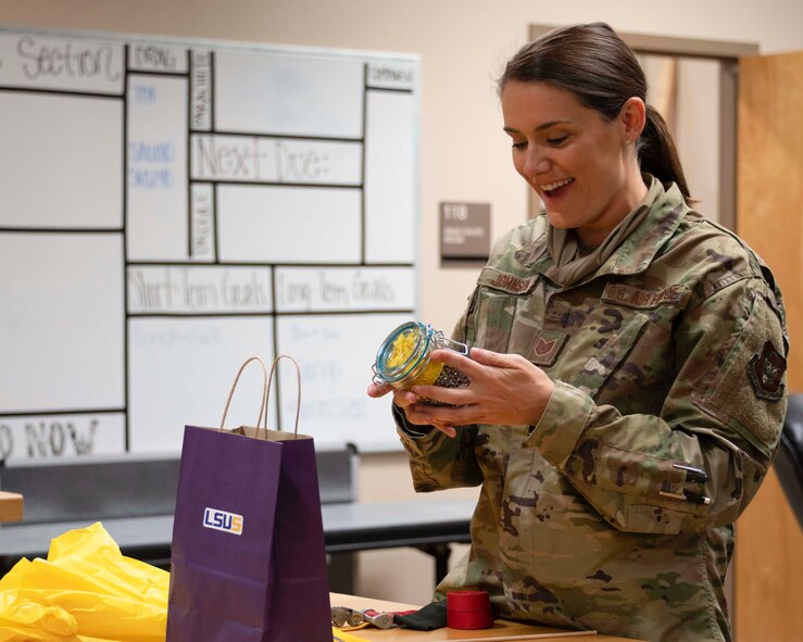 Photo of Airman smiling as she holds a jar of primers.