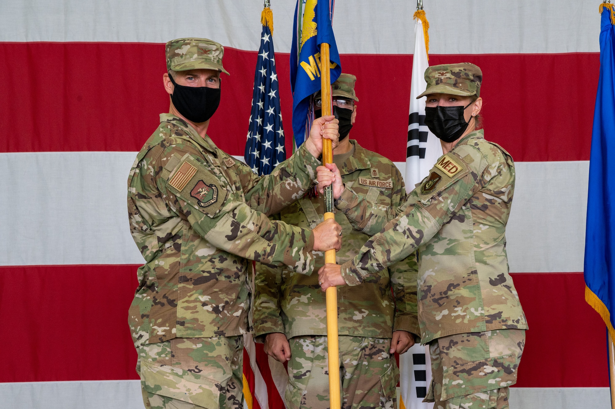 Col. Joshua Wood, 51st Fighter Wing commander, left, presents Col. Jennifer Vecchione, with the 51st Medical Group guidon during the change of command ceremony at Osan Air Base, Republic of Korea, July 12, 2021. This act marks the official beginning of Vecchione’s command of the 51st MDG. (U.S. Air Force photo by Tech. Sgt. Nicholas Alder)